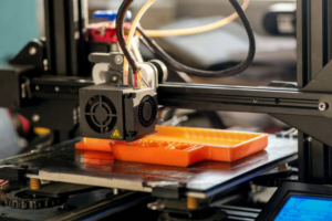 3D printer prints orange plastic model