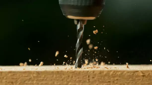 Freeze motion of a drill bit drilling into wood, macro shot
